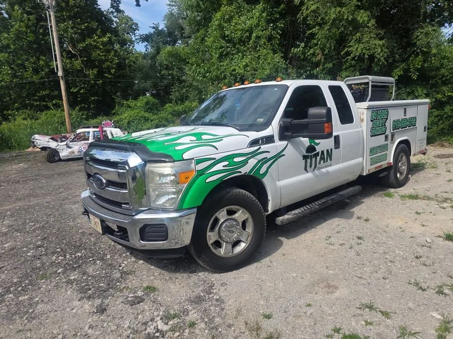 The Titan mobile service truck — a white Ford with green flame livery, its service body lettered 24 hour heavy towing and mobile truck and trailer repair.